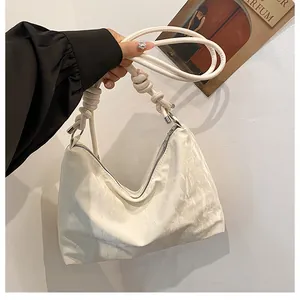 Close-up of cream-white hobo bag with pleated leather texture and knotted shoulder strap