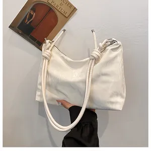 Detail of white pleated shoulder bag with unique thick rope knot handle design