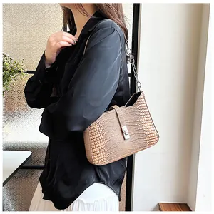 Detail of light brown crocodile pattern underarm bag with silver chain strap and metal clasp