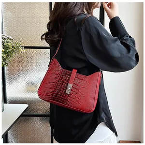 Detail of red crocodile pattern shoulder bag featuring a sleek metallic twist lock