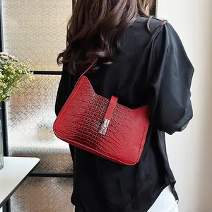 Detail of red embossed leather underarm bag with silver lock on a female model