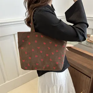 Brown corduroy tote bag with red strawberry print shown in a stylish side view profile