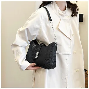 Detail of black crocodile texture bag with silver twist lock and chain strap