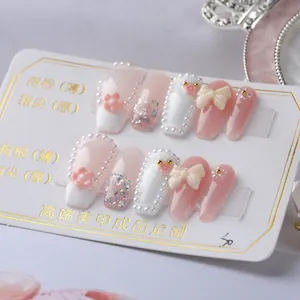 Macro detail of long coffin press-on nails with 3D bows, pink flowers, and pearls