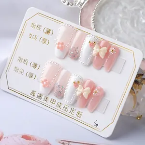 Macro detail of handmade pink press-on nails with 3D flowers, pearls, and glitter