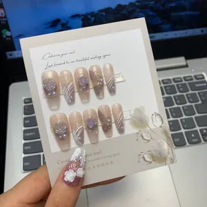 Macro shot of handmade press-on nails with 3D roses, pearls and butterfly nail art
