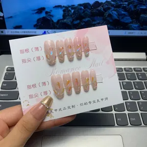Detail of long coffin press-on nails with aurora glitter and gold foil on pink display card