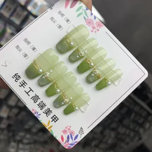 Detailed view of handmade green gradient press-on nails with pearls and gold floral decor