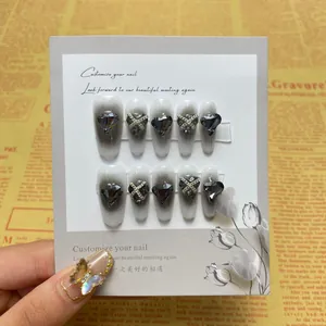 Detail of dark press-on nails with black gradient, heart rhinestones and silver chains