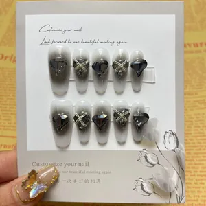 Detail showing creamy white nails with black gradient, heart rhinestones and silver chains