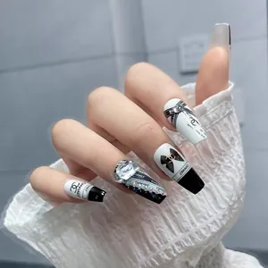 Detail of luxury black and white press-on nails with rhinestone and bow accents