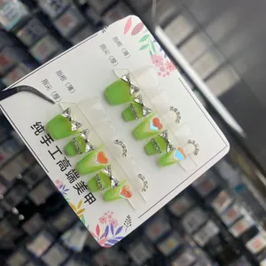 Detailed set of 10 handcrafted green press-on nails with silver bows and red heart gems