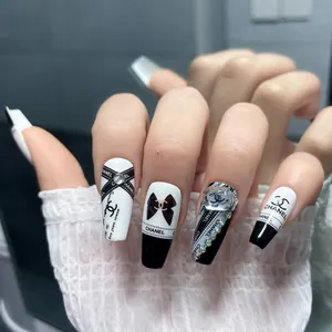 Detail of long coffin nails with black heart rhinestones and luxury chain accents