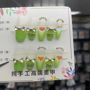 Detail of handmade press-on nails in light green with 3D silver bow and rhinestone accents