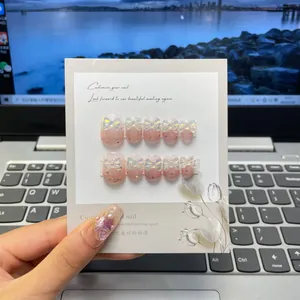 Détail de faux ongles dégradés roses avec papillons laser 3D et breloques de roses