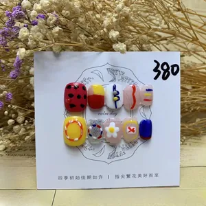 Macro detail of handmade press-on nails featuring red polka dots and floral patterns