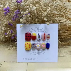 Macro shot of 10pcs assorted press-on nails with 3D daisies and polka dots on display card