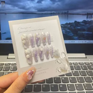 Macro view of handmade purple amethyst butterfly press-on nails with 3D white floral art