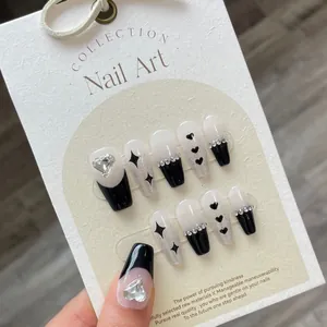 Press-on nails with black hearts, glitter stars, and rhinestones on textured card