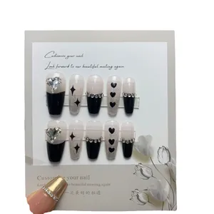 Black and white press-on nails with heart rhinestones and star glitter in coffin shape