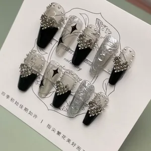 Detailed view of handmade black and silver chrome heart style press-on nails with metal studs