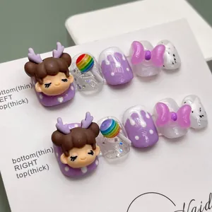 Détails macro de faux ongles 3D violets faits main avec figurines et sucettes arc-en-ciel