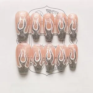 Detail of 10-piece press-on nails with pink gradient, silver glitter and white flame motifs