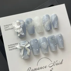 Dettaglio di unghie finte fatte a mano con rilievo di angelo 3D e rose blu opaco