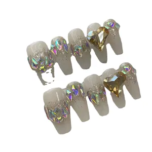 Faux ongles faits main avec cristaux en cœur et paillettes argentées sur base nude