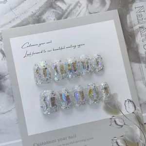 Makroansicht von silbernen Glitzer-Klebenägeln mit holografischen Steinen und Blumenkarte