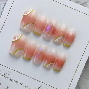 Close-up of handmade press-on nails with 3D lemon art and pink gradient finish