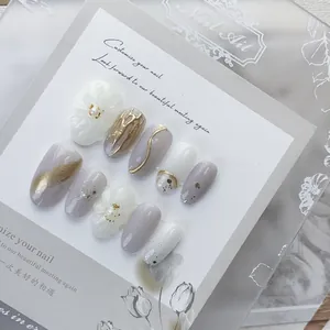 Handmade press-on nails with 3D gold accents, white floral patterns and marble texture