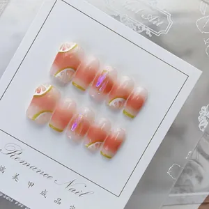 Detailed view of handmade pink gradient press-on nails with lemon art and iridescent foils