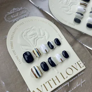 Close-up of black and white press-on nails with blue stripes and glossy finish details