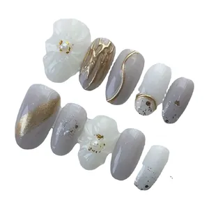 Handmade press-on nails with 3D floral accents and gold waves in soft white and grey