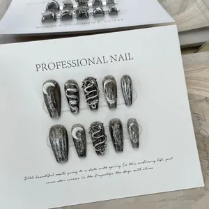 Detail of handmade coffin nails with 3D silver dragon and moon charms on dark marble base