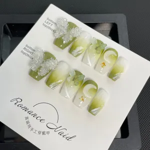 Détail de faux ongles faits main vert dégradé avec papillons 3D et décorations en feuille d'or