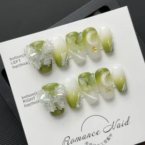 Vue macro des ongles dégradés vert et blanc avec papillons en cristal 3D