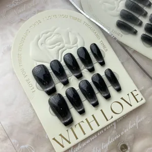Close-up of handmade black cat eye press-on nails in long coffin shape on a rose card