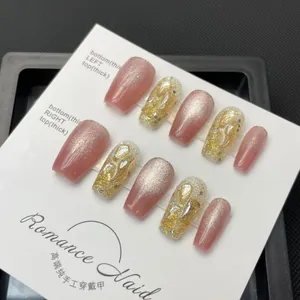 Close-up of handmade coffin shape press-on nails with pink glitter and 3D gold accents