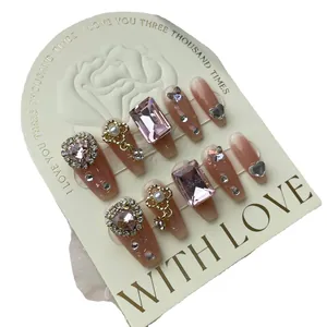 Luxurious nude pink gradient press-on nails with sparkling rhinestones and heart charms