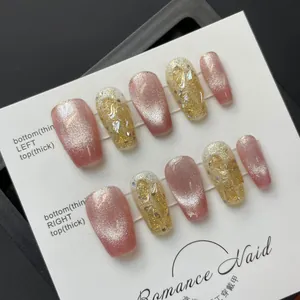 Detailed view of handmade pink cat-eye press-on nails with gold foil on white card