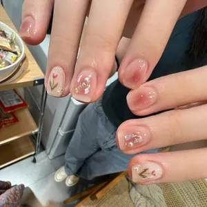 Handmade press-on nails with tulip art, pearls, and blush gradient in a short square shape