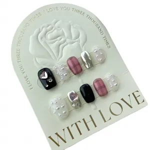 Faux ongles faits main à carreaux noirs et roses avec strass en cœur et perles