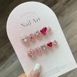 Handmade raspberry red press-on nails with heart rhinestones and glitter finish