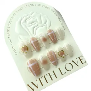 Handmade press-on nails featuring creamy pink gradient, pearl accents and gold heart charms