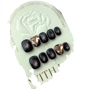 Handmade black cat-eye press-on nails with large heart diamond accents on display card