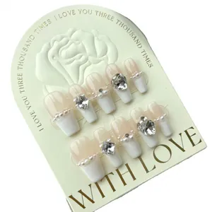 Elegant nude French press-on nails set with pearls and rhinestones on rose card