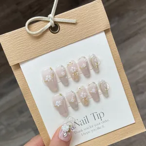Faux ongles faits main œil-de-chat avec fleurs 3D et perles sur dégradé rose nude brillant