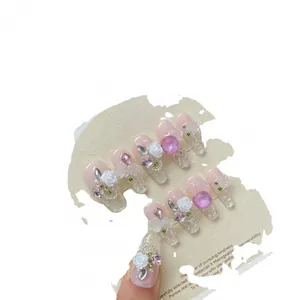 Handmade press-on nails with 3D camellia flowers and pink rhinestones on a display card